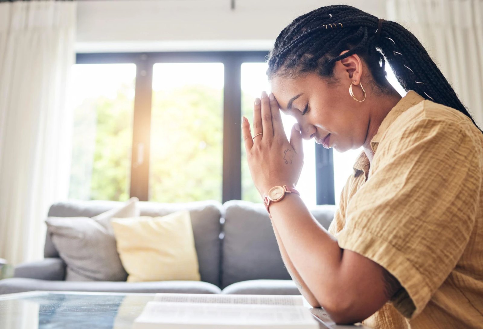 A woman praying over her Bible at home